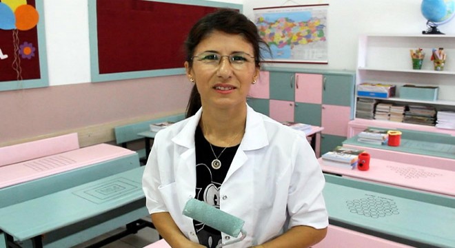 Derya öğretmen, sınıfındaki sıraları onarıp, boyadı