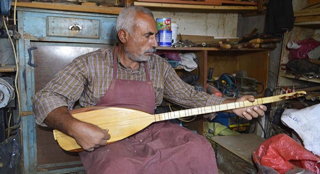 Evinin bodrumunda kurduğu atölyede saz yapıyor