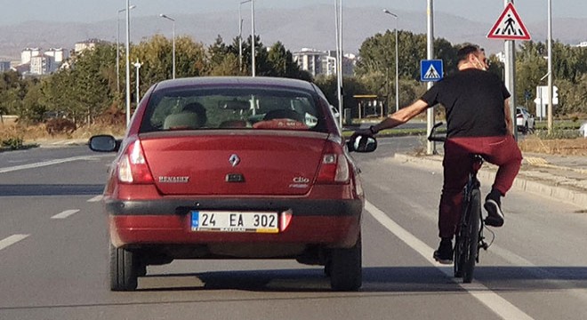 Otomobilin aynasına tutunan bisikletlinin, tehlikeli yolculuğu