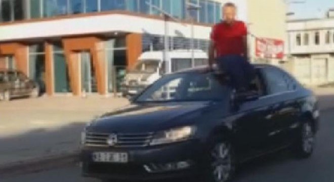 Otomobilin tavanına oturup, direksiyonu ayağıyla kontrol ederek araç kullandı