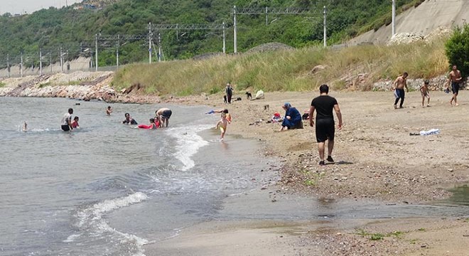 Simsiyah akan derenin kirlettiği plajda, denize girdiler