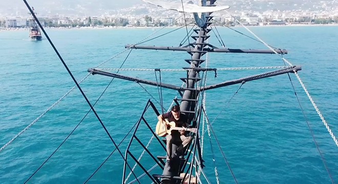 Teknenin tepesinde gitarla Alanya tanıtımı yaptı