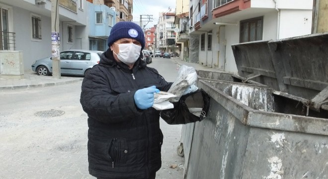 Yerlere atılan maskeleri topluyor